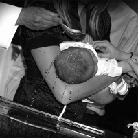 © Divine in the Daily (flickr.com) Ein Baby, das gerade mit Weihwasser übergossen wird.
