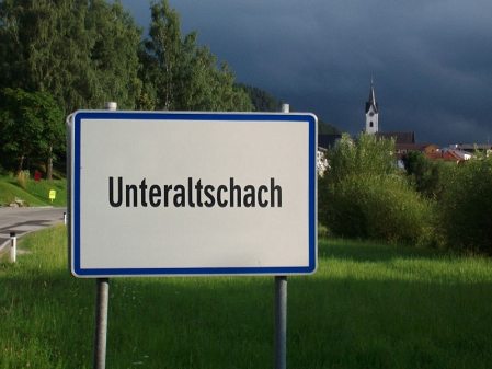 © FM4 (Robert Haslinger) Eine Ortstafel am Ortseingang von Unteraltschach mit Kirchturm dahinter