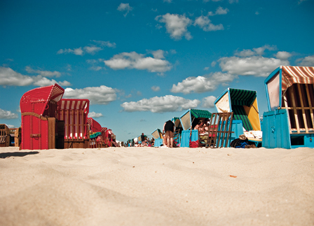 © Katharina Tanzberger heller strand auf usedom, rote und blaue strandkoerbe, blauer himmel mit weissen wolken