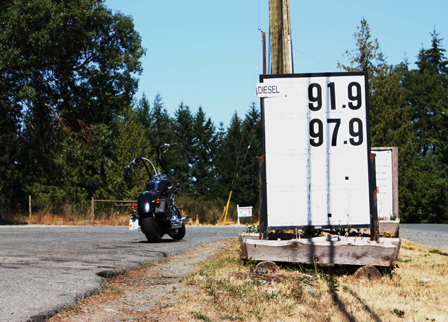 © Anna Theil motorrad an einer verlassenen tankstelle mit preistafel im wald