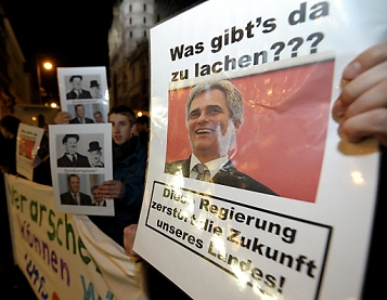 © APA HERBERT P. OCZERET A protester holds a picture of Chancellor Faymann