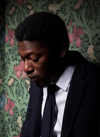 © rootsmanuva roots manuva vor einer Blumentapete