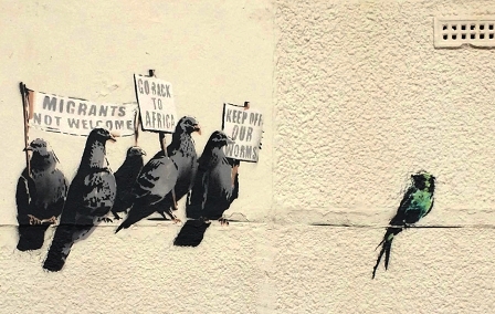© banksy.co.uk Tauben mit Schildern "Go Back To Africa", "Migrants not welcome", "Keep off our worms" auf Telegrafenleitung neben Zugvogel