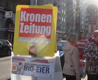 Krone-Zeitungssackerl, hinten eines  vom Kurier, im Sonnenlicht.