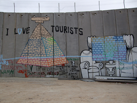 Graffitis auf Mauer - "I love tourists" und eine Pyramide sowie ein gemütliches Wohnzimmer aus dessen Fenster man eine Ziegelmauer sieht