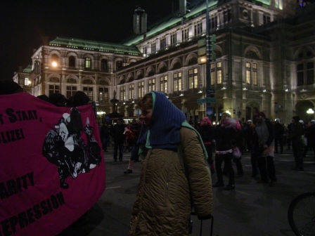 Eine ältere Dame betrachtet ein Demontrationstransparent vor der Wiener Staatsoper.