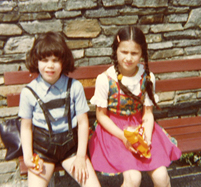 Riem Higazi, age 6 wearing a dirndl and sitting next to her brother Tamer Higazi, aged 5 wearing lederhosen.