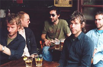 © The National Die Band The National an einem Tisch sitzend