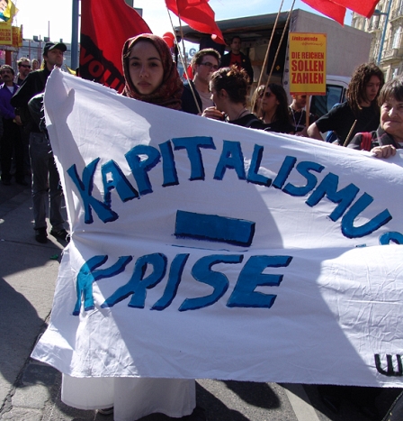 Demo in Wien, Leintuch, auf dem "Kapitalismus = Krise" steht wird von einer jungen Frau gehalten