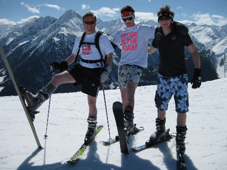 drei Männer in kurzen Hosen auf der Schipiste.