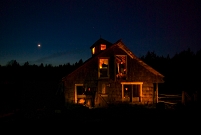 Hütte im Wald, in jedem Fenster ein Mitglied der Band "Wolves In The Throne Room"