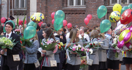 Mädchen in Uniform mit Blumen und Luftballons.