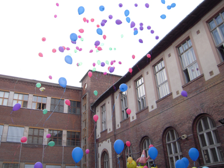 Der Innenhofs der Xantus János Tourismusschule mit Luftballons, die in den Himmel aufsteigen.