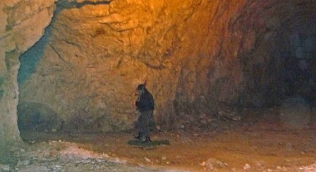 person with a gun over his shoulder walks in the caves of the former concentration camp in Ebensee 