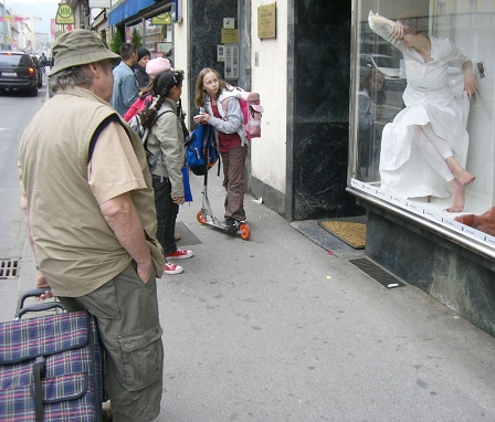 Passanten schauen auf im Schaufenster sitzendes lebendes Model