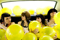 Die Band The Coathangers inmitten von gelben Luftballons