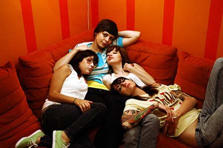 The Coathangers liegen auf einem roten Sofa