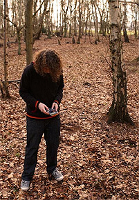 Chiptunes-Künstler "Superpowerless" mit Game Boy im Wald.