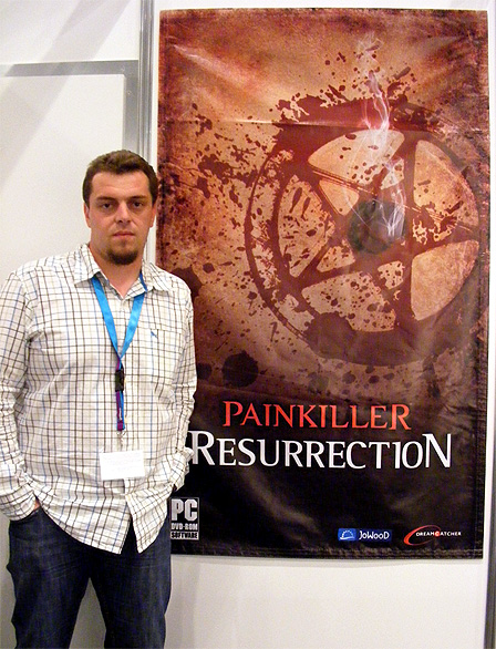 Spieleentwickler Johann Ertl vor einem Plakat zu "Painkiller Resurrection".