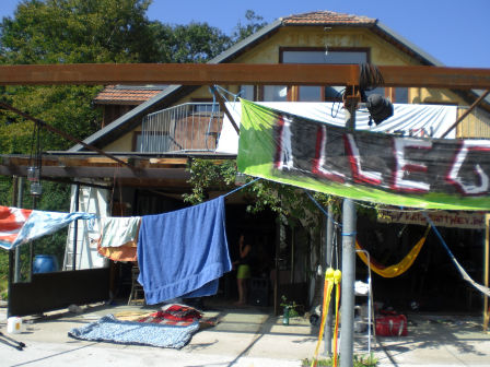 Wäscheleinen mit Wäsche und Demo-Transparenten vor einem Holzhaus.