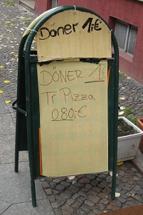 ein schild, das döner um 1 euro und türkische pizza um 80 cent bewirbt