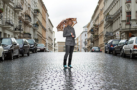 Eine Frau mit Regenschirm mitten auf einer regennassen Straße