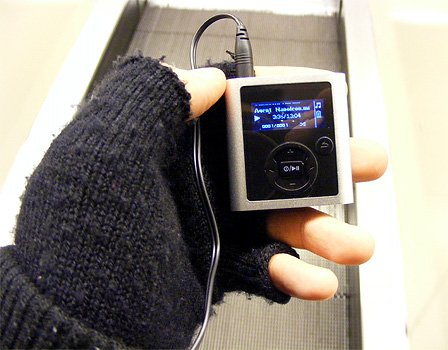 Ein kleiner MP3-Player in einer Hand, im Hintergrund ein Rollband.