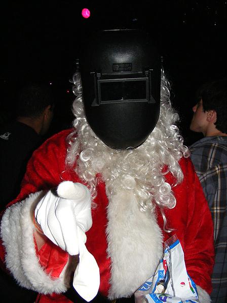 Ein Weihnachtsmann mit Schweißermaske zeigt mit dem Finger.