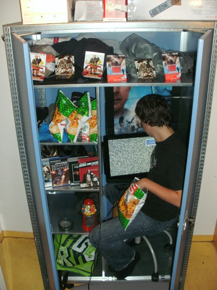 junger mann in einem schrank mit zwei flügeltüren, chips essend, filme schauend