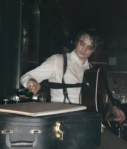 Pete Doherty sitzt auf der Bühne und schenkt sich Glas Bier ein