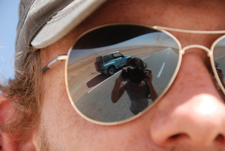 Sonnenbrille, in der sich Fotografin und Auto spiegeln