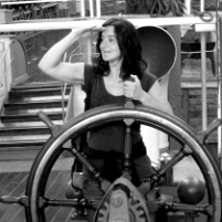 Ingrid Gollackner steht hinter einem grossen schiffssteuerrad 