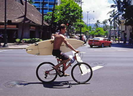 radfahrer, der ein surfboard unterm arm geklemmt hat
