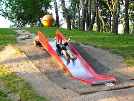 Junger Mann rutscht auf einem Spielplatz