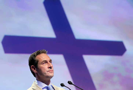 hc strache vor einem blauen kreuz