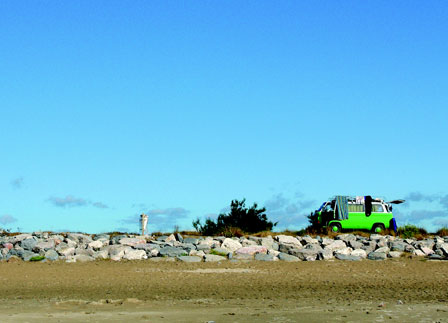 gruener alter vw campingbus steht an einem strand handtuecher haengen auf dem bus sehr viel blauer himmel