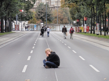 Auf der gesperrten Ringstraße sitzt ein junger Mann und telefoniert.