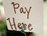 Schild mit Aufschrift: Pay Here