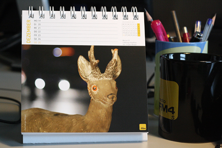 fm4 stehkalender auf schreibtisch mit goldenem hirsch als motiv