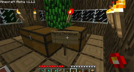 Ein Zimmer in einem Haus in "Minecraft". In der Mitte des Raumes steht ein Schild mit der Aufschrift "Merry Christmas", daneben stehen drei große Geschenkspakete.