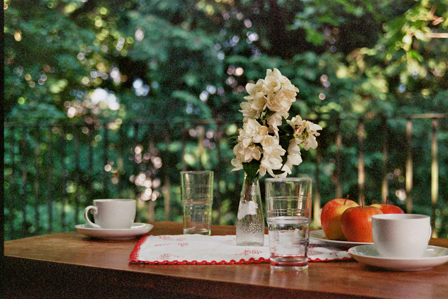 © sophie plainer tisch auf balkon mit tassen, glaesern, blumen u aepfeln