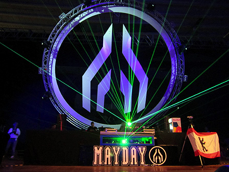 Die Retro-Bühne auf der 20. Mayday. Man sieht den Schriftzug "Mayday", Stroboskop-Laser, das große "Mayday"-Logo in Form eines Flugzeuges von oben und eine Flagge von Berlin.