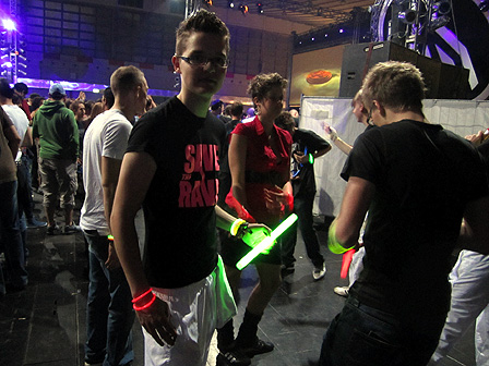 Ein junger Besucher, der einen gelben glow stick in der Hand hält und auf dessen T-Shirt "Save the rave" geschrieben steht.