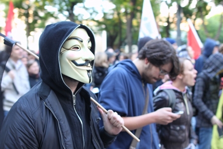 © Simon Welebil Person mit schwarzem Kapuzenpullover und Guy Fawkes Maske