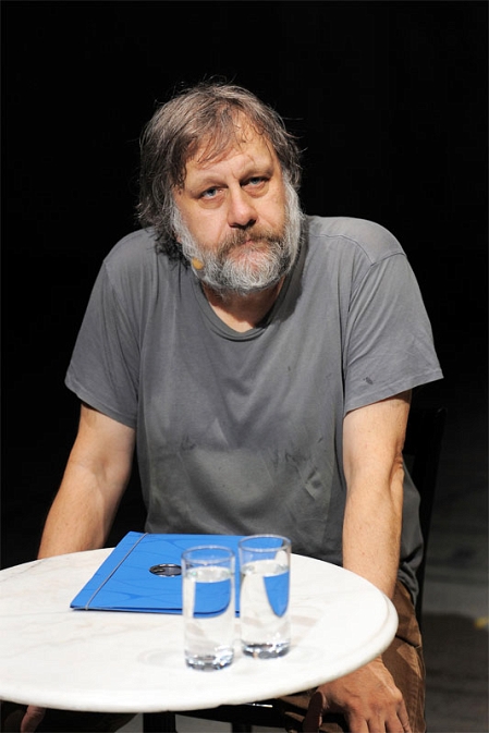 slavoj zizek an einem tisch sitzend