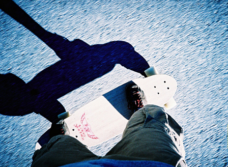 © georg wallner blick auf fuesse auf einem longboard auf der strasse mit schatten