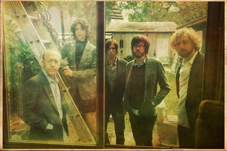 Die Band Okkervil River in einem Hinterhof, durch ein Fenster fotografiert