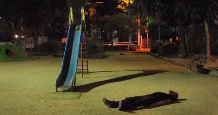 Bensh auf einem Spielplatz vor einer Kinderrutsche am Boden liegend