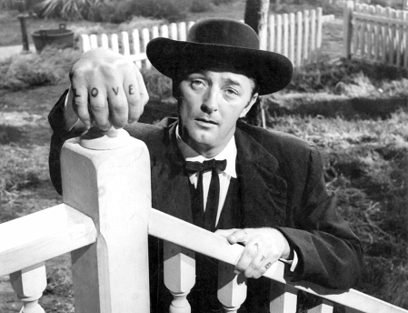 Robert Mitchum an einer Verand alehnend in dem Film "The Night of the Hunter"