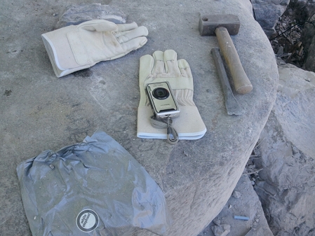 Hammer und Meißel und Arbeitshandschuhe liegen auf Stein an der Mur